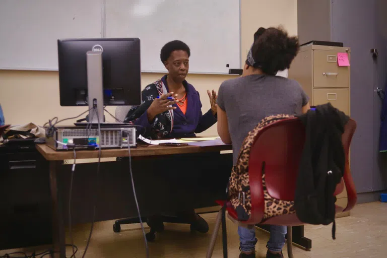 2 people sitting at a desk facing each other with a computer between them