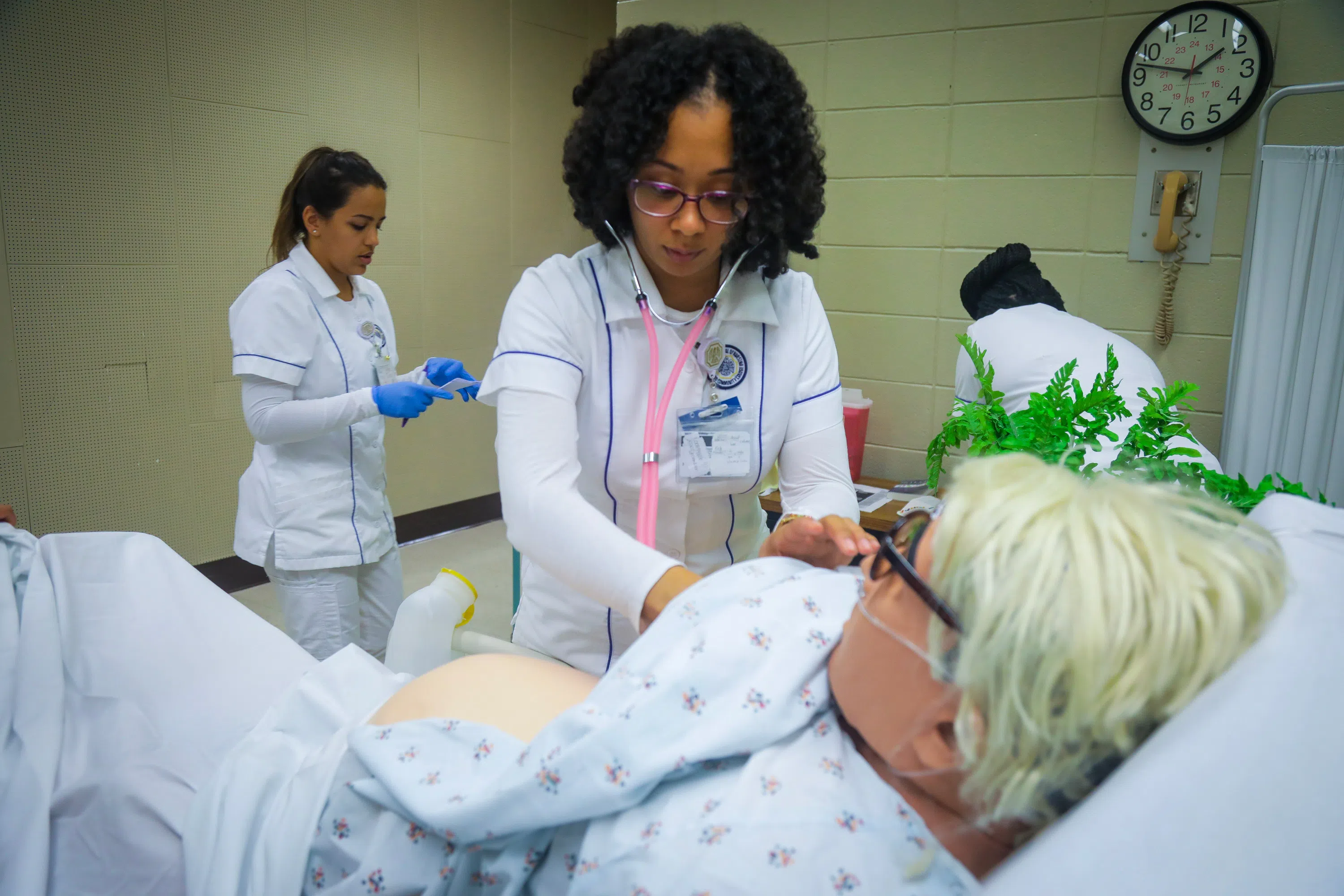 nursing student checking vitals on an adult practice dummy
