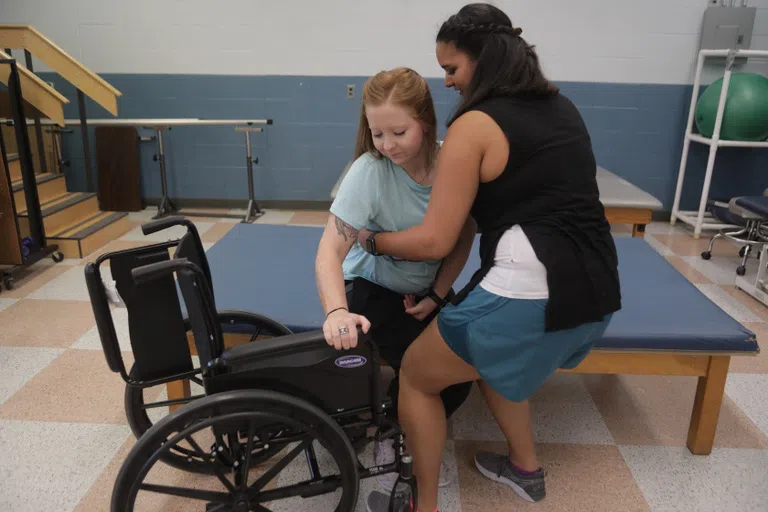 person helping another into a wheelchair