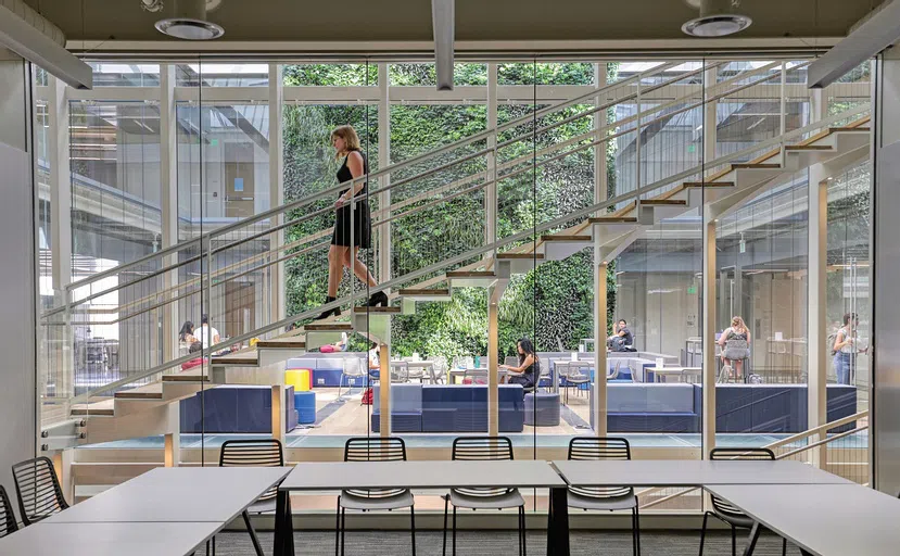 A person walks down the stairs in front of the two-story living wall