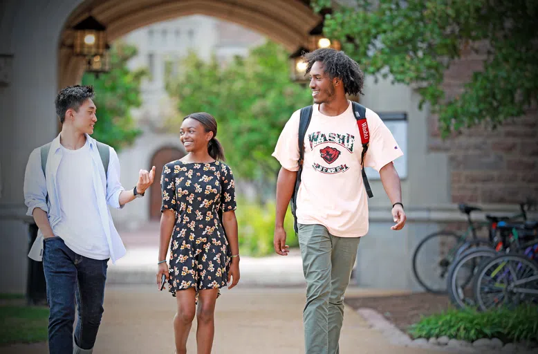 Three students walk in front of the archway at McMillan Hall