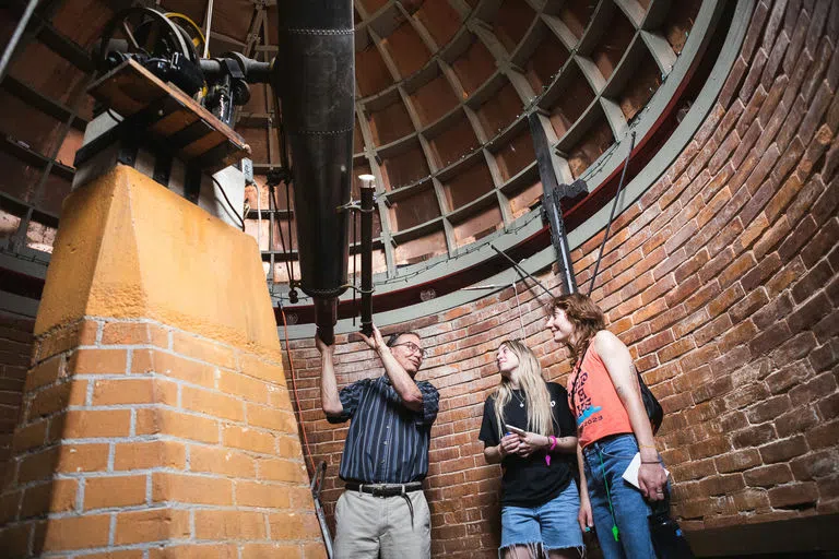 Students viewing the telescope inside of the observatory