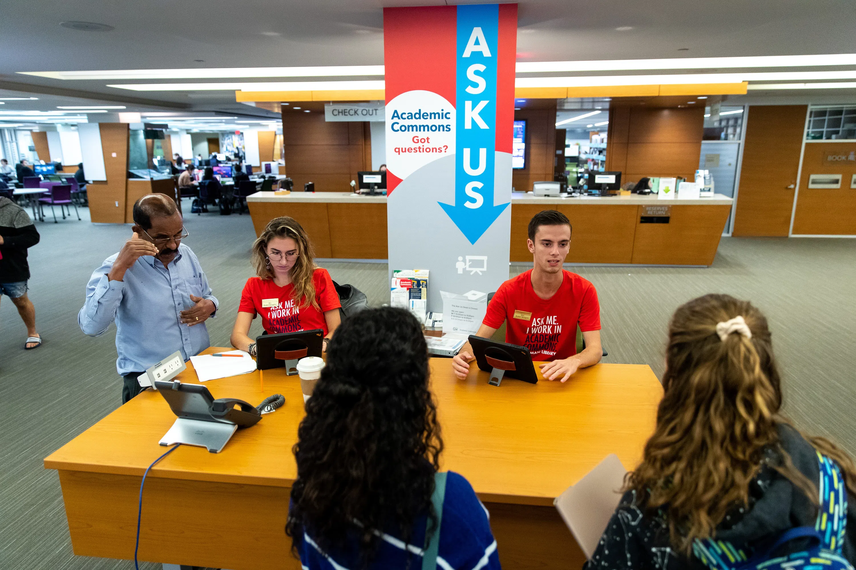 Student workers at the Academic Commons desk assist guests. 
