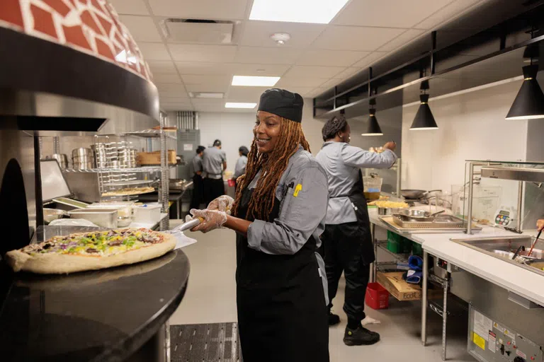 A dining staff member makes a pizza in Thurston!