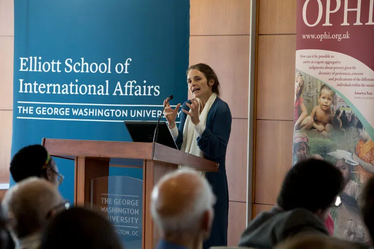 A woman stands at a podium and gives a presentation inside the Elliott School of International Affairs.