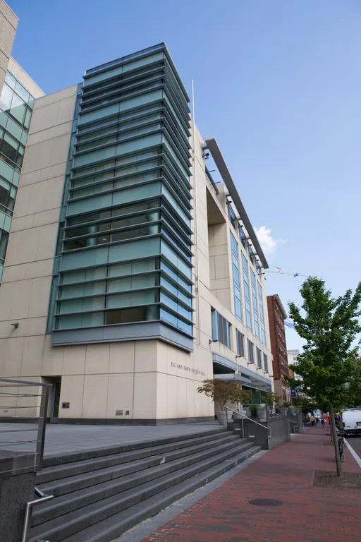 Exterior view of Duquès Hall with stairs and trees. 