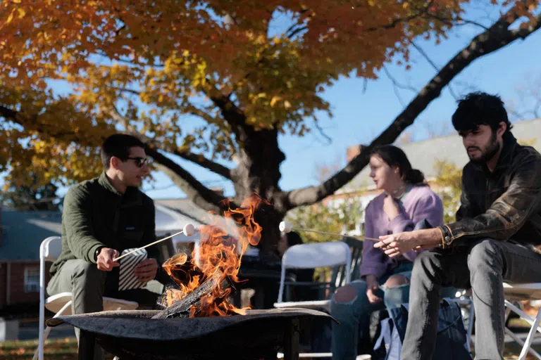 Students warm smores over a fire pit on the Mount Vernon quad