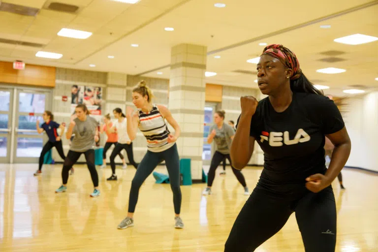 Students take a group fitness class in a gym studio. 