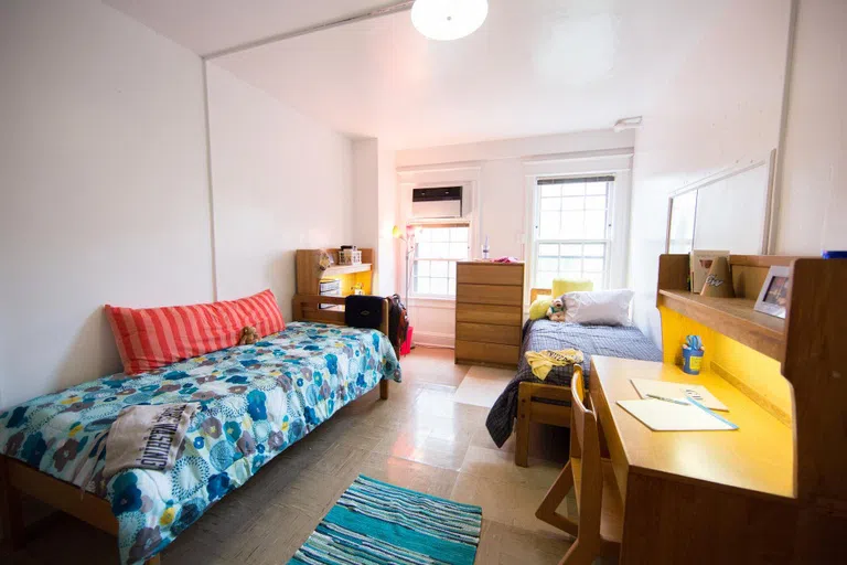 A typical room in Madison Hall, with 2 twin beds, 2 desks and chairs, a dresser, and 2 windows.