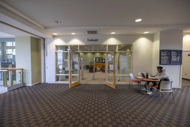 Entrance to Library on the second floor of Building A. Student sits off to the right of the entrance, studying at a table. 