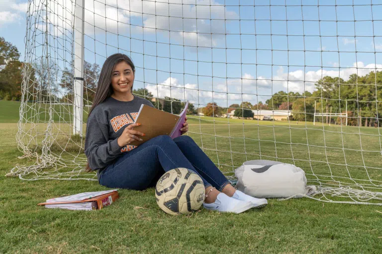 Student studies from her notebook behind the soccer goal