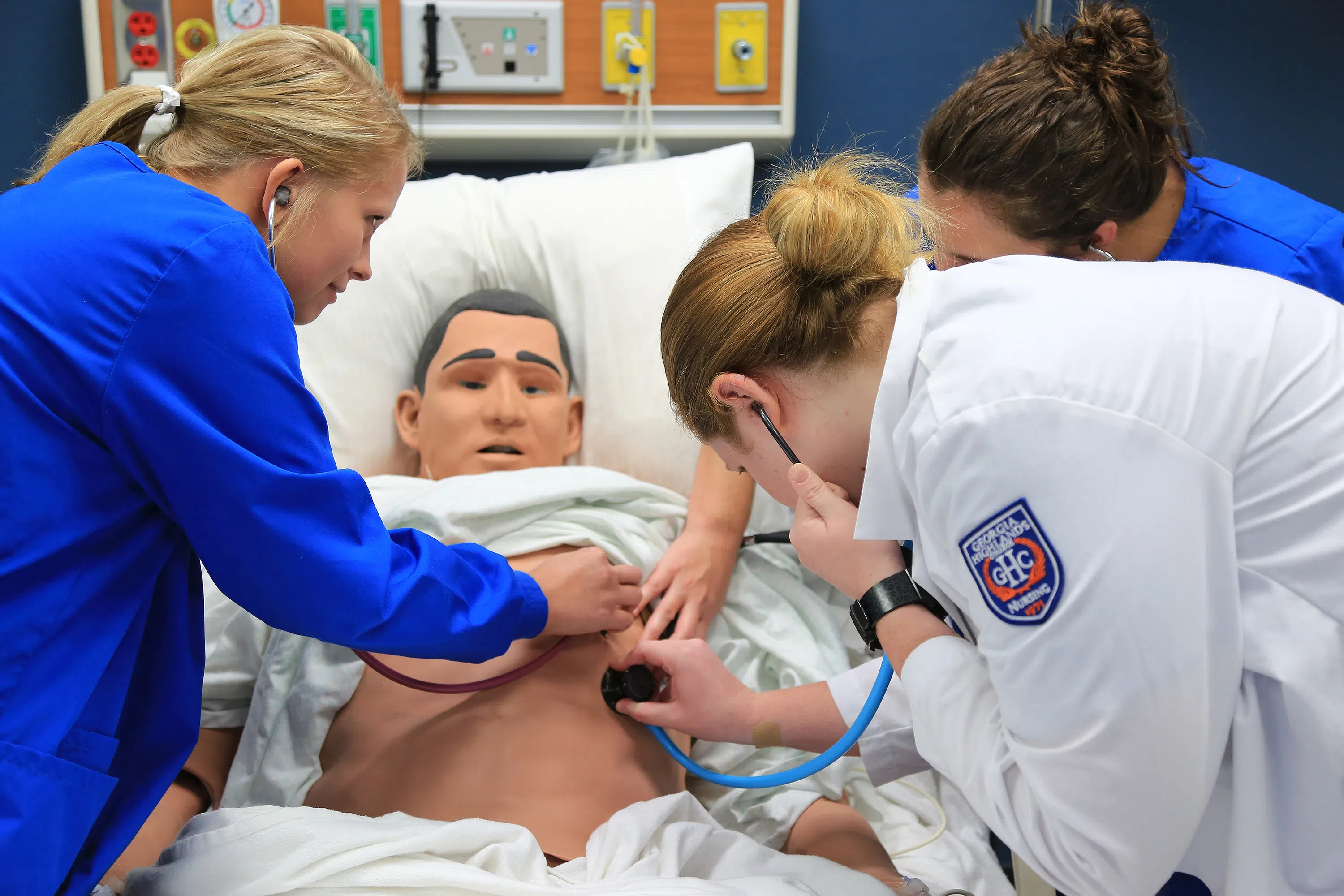 Student examine dummy patient in hospital bed