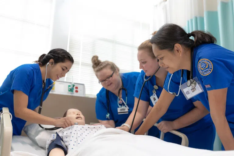 A group of nursing students examine a mock patient