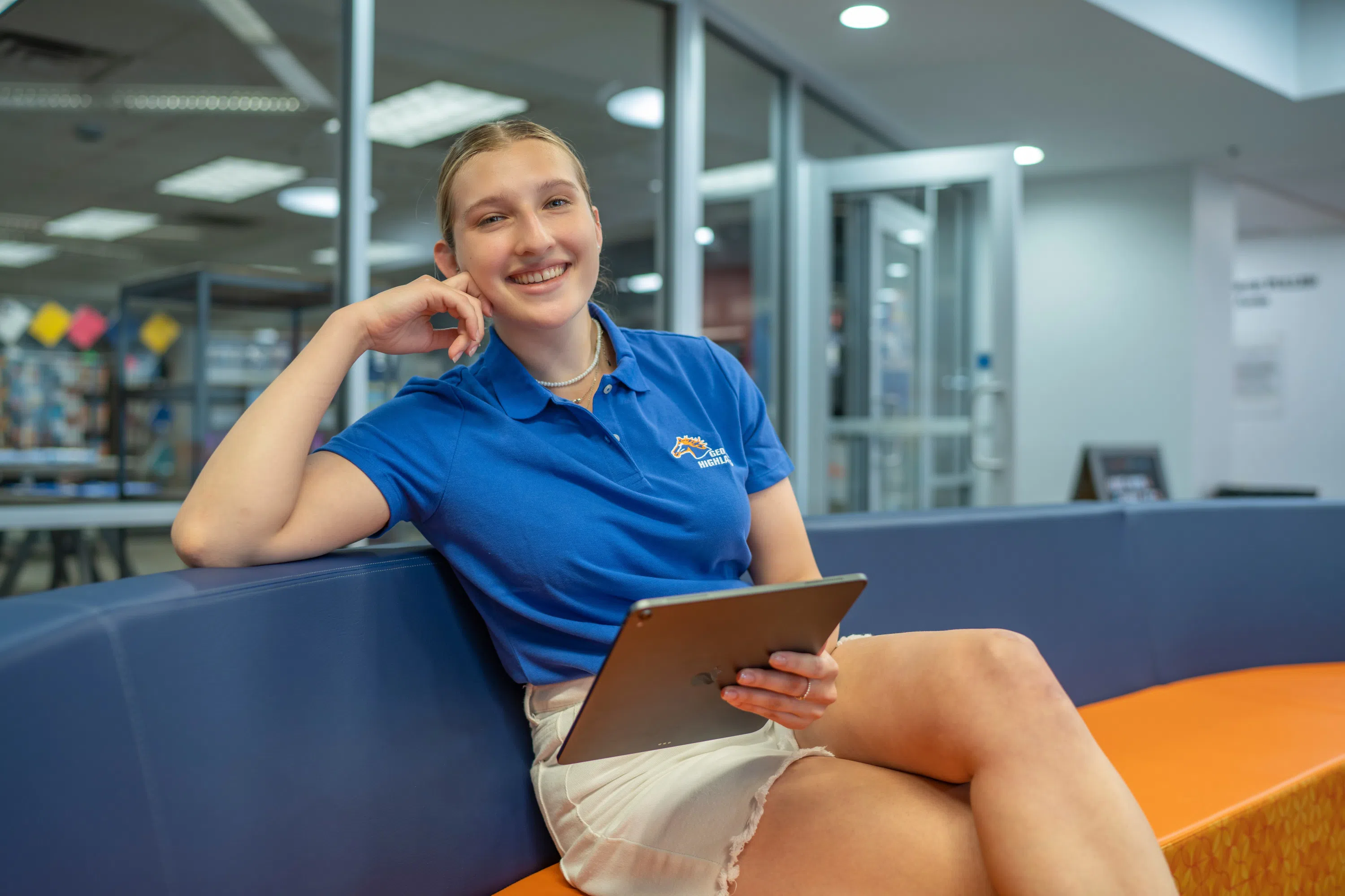 Student smiles at the camera while holding an iPad