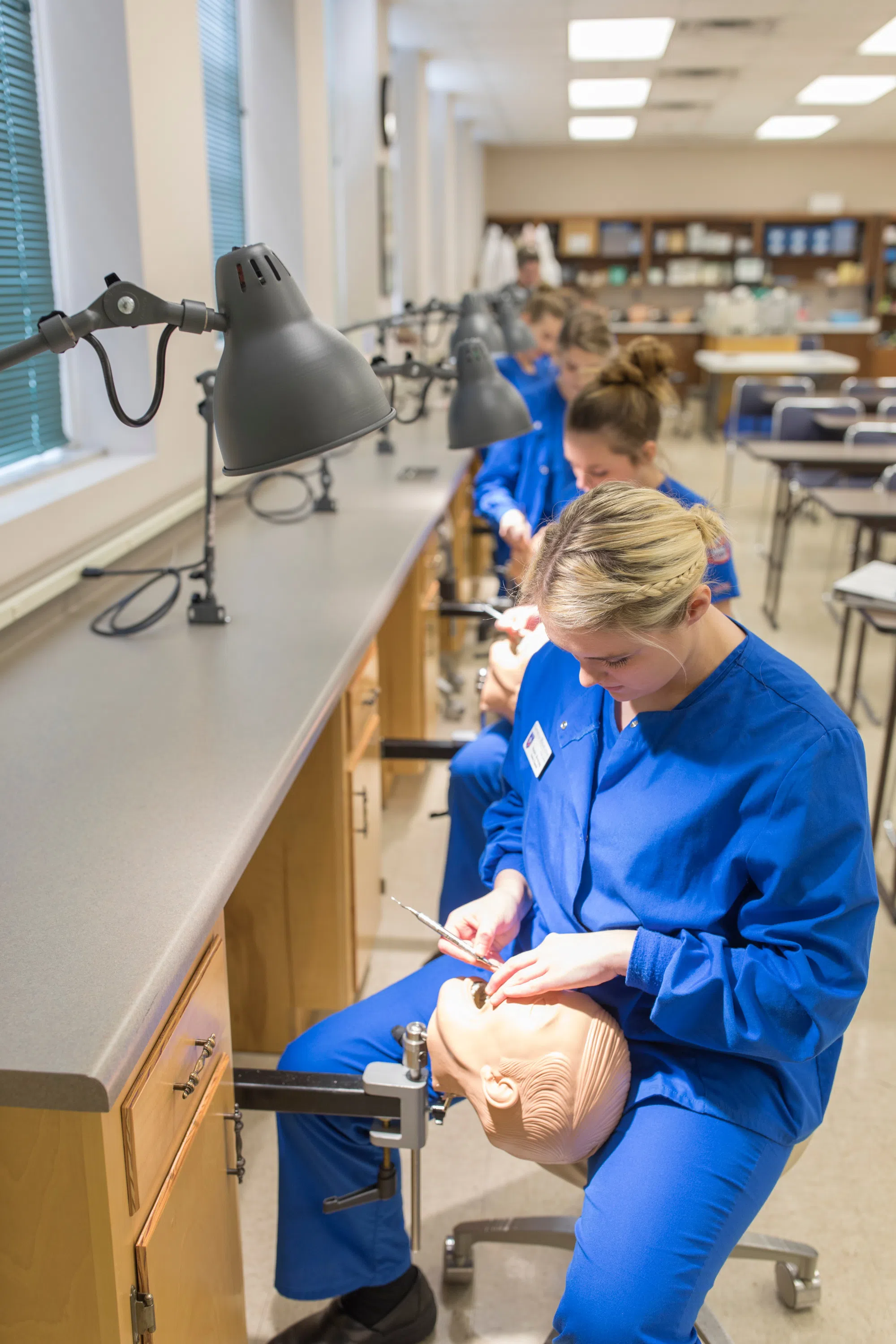 Dental students practice cleaning teeth on fake patients 