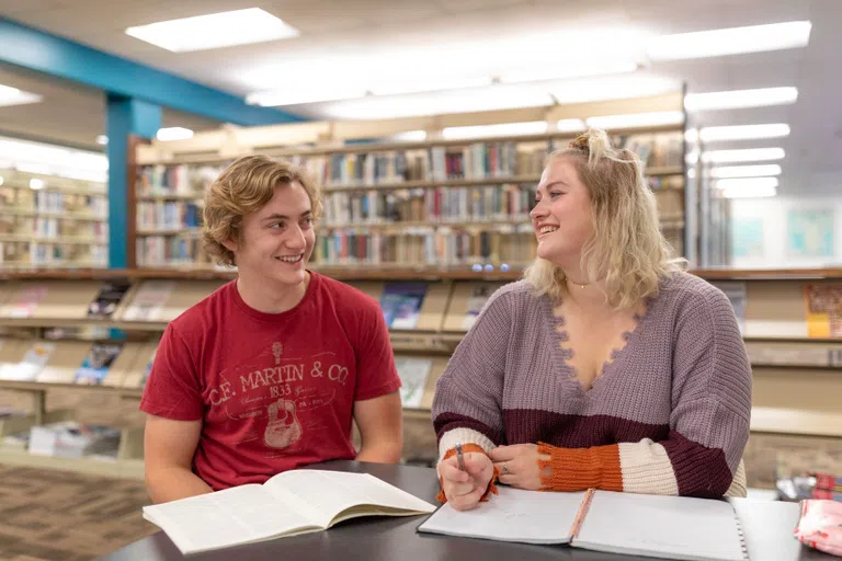 Two students work together with books in front of them