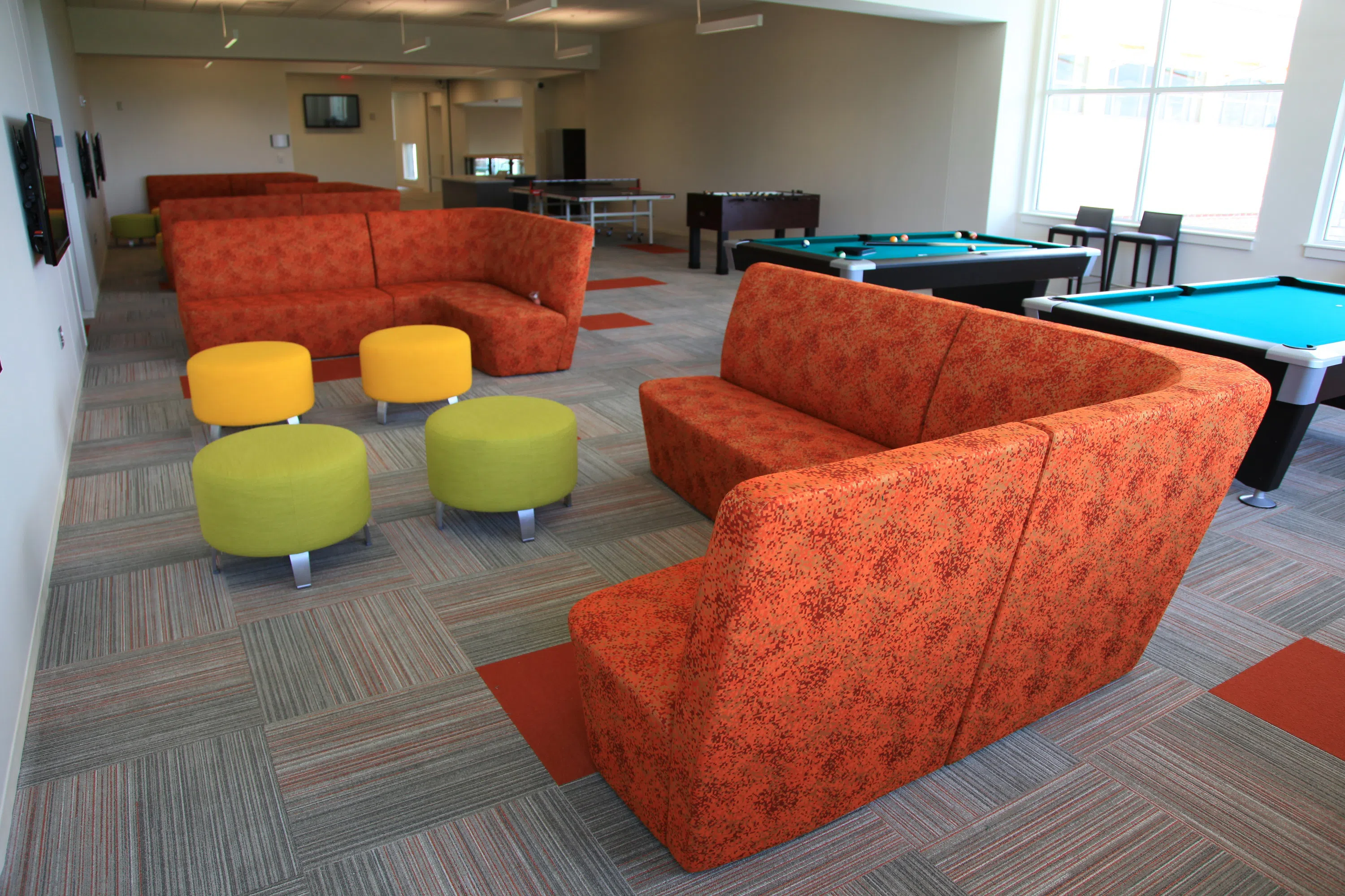 Comfy orange couches in a semi-circle in the game room