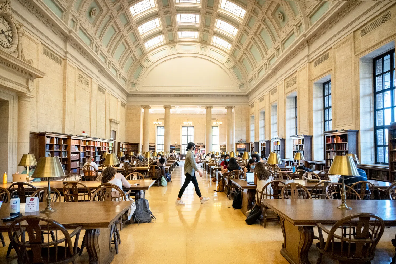 Students study at wooden tables in a well-lit domed library room.