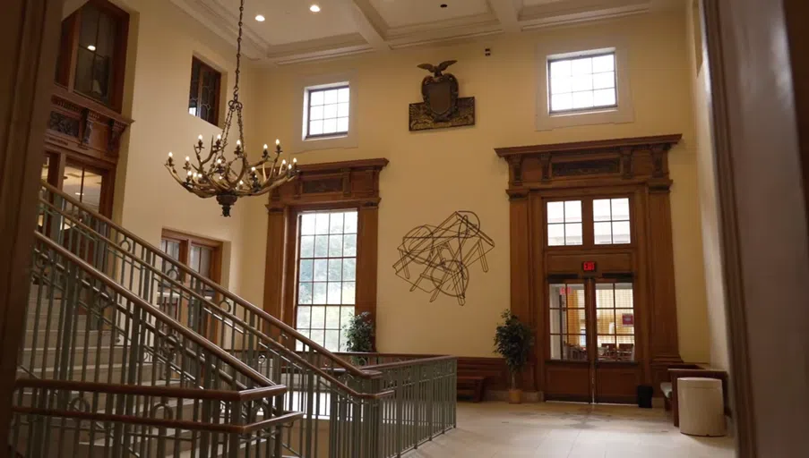 Interior shot with two large doors, a stairwell on the floor, and large chandelier