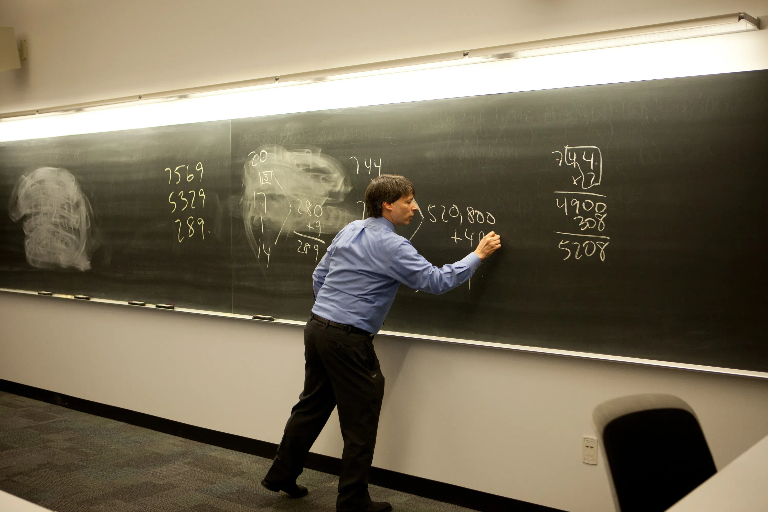 Math professor on black chalkboard