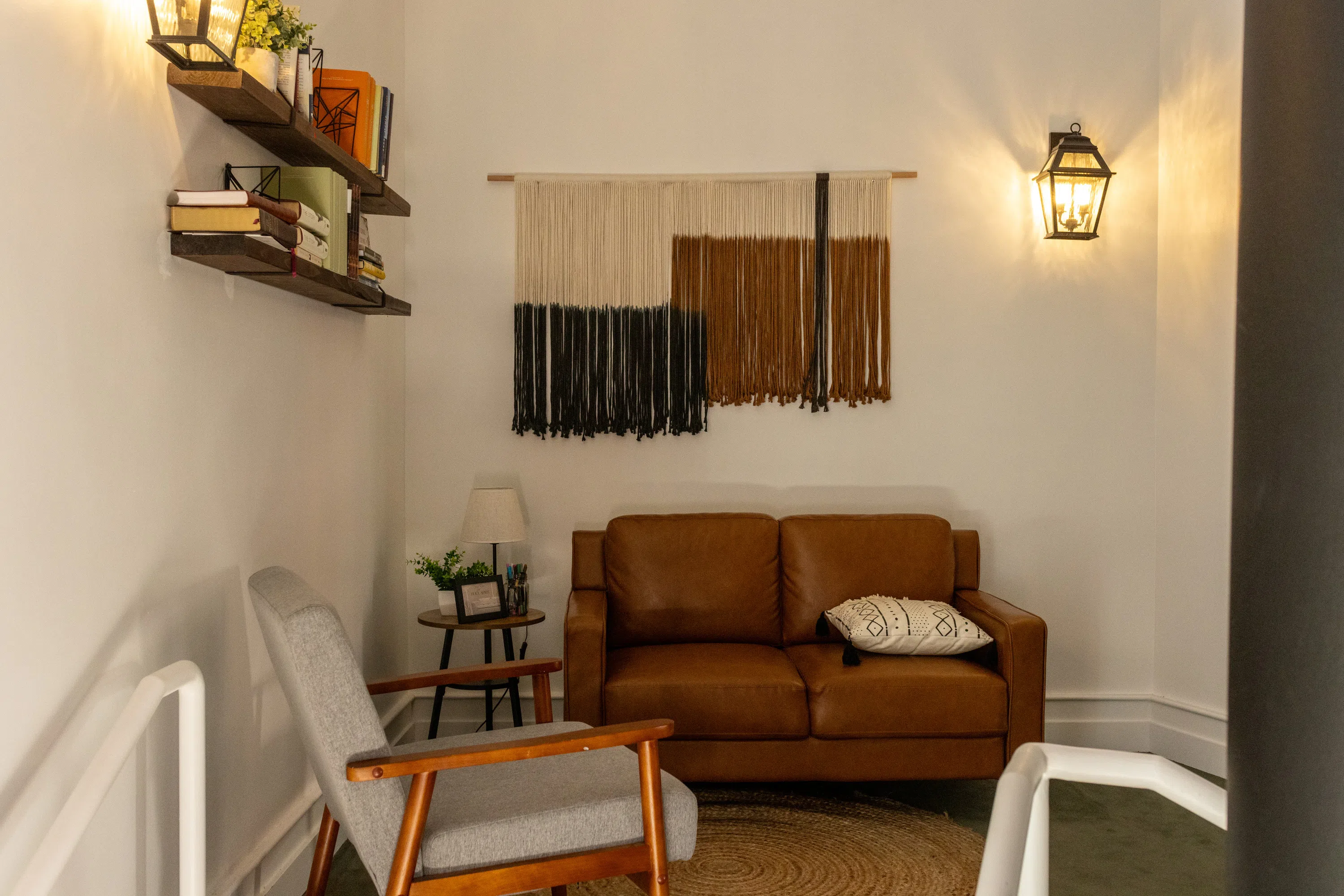 Seating area with leather couch and grey chair. shleves and decorations