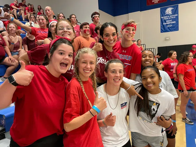 Students smiling and posing for the camera while on athletic bleachers