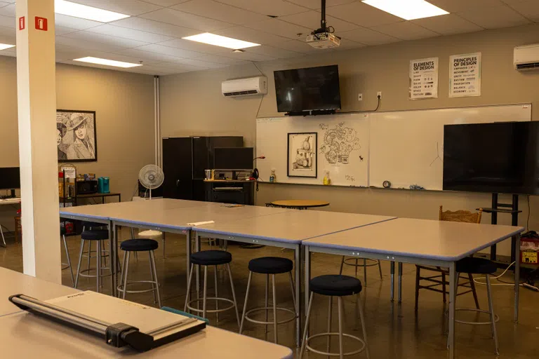 Drafting tables with stools inside a room with a large whiteboard