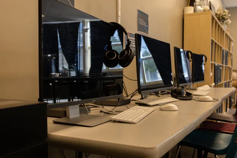 row of computers with headphones hung on screen