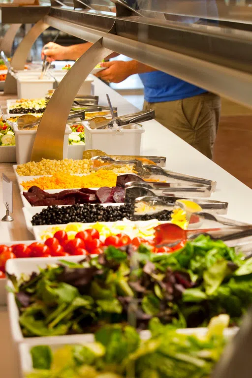 Treys of food laid out on a salad bar