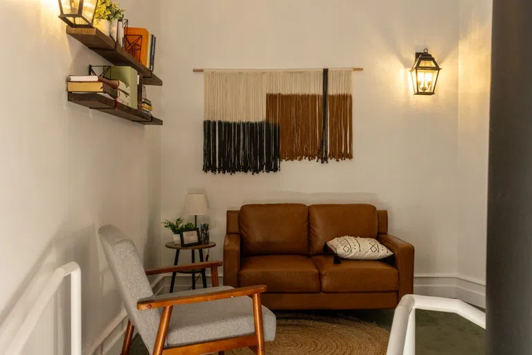 Seating area with leather couch and grey chair. shleves and decorations