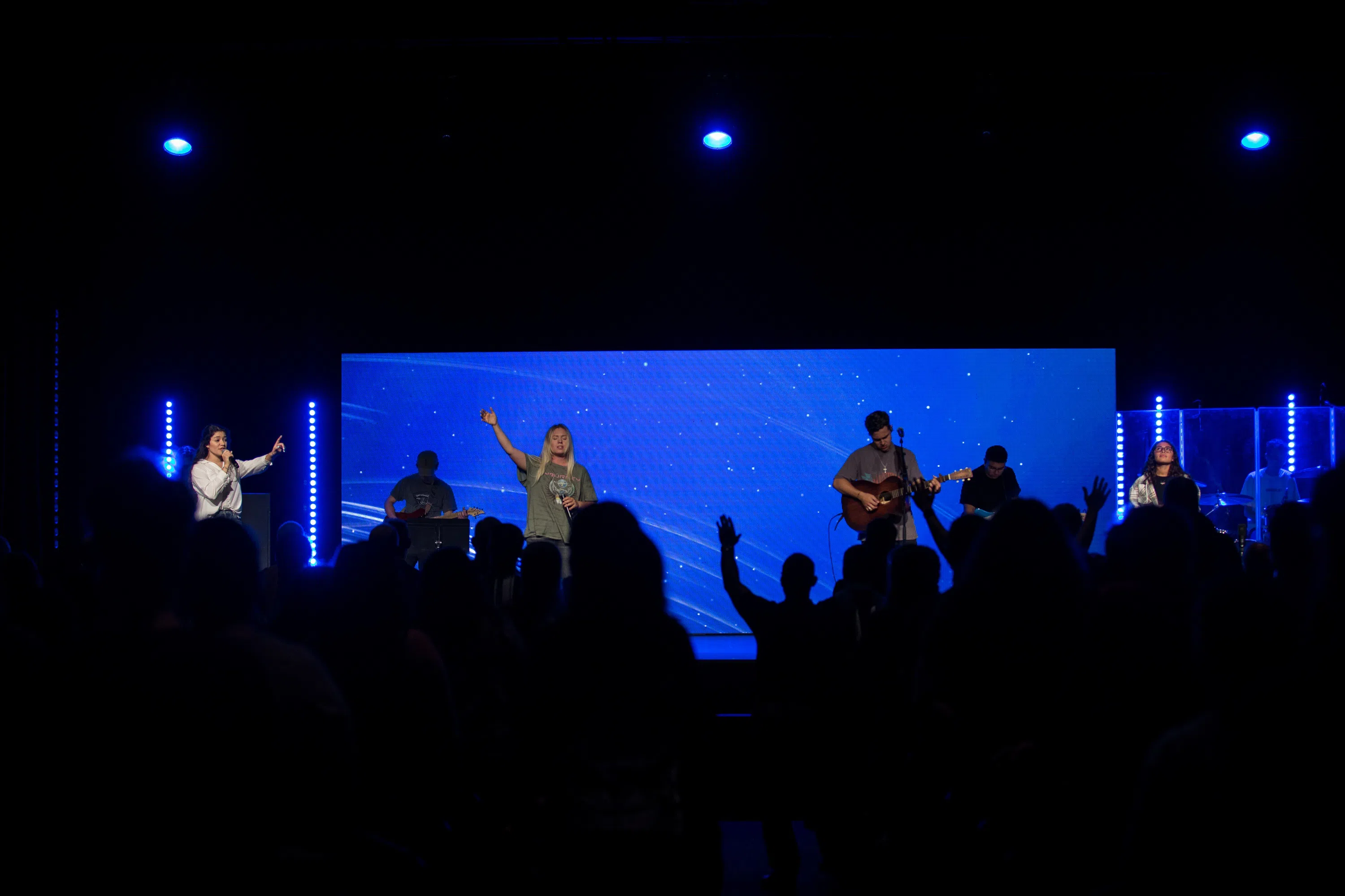 Performance on stage with live music. People raising hands