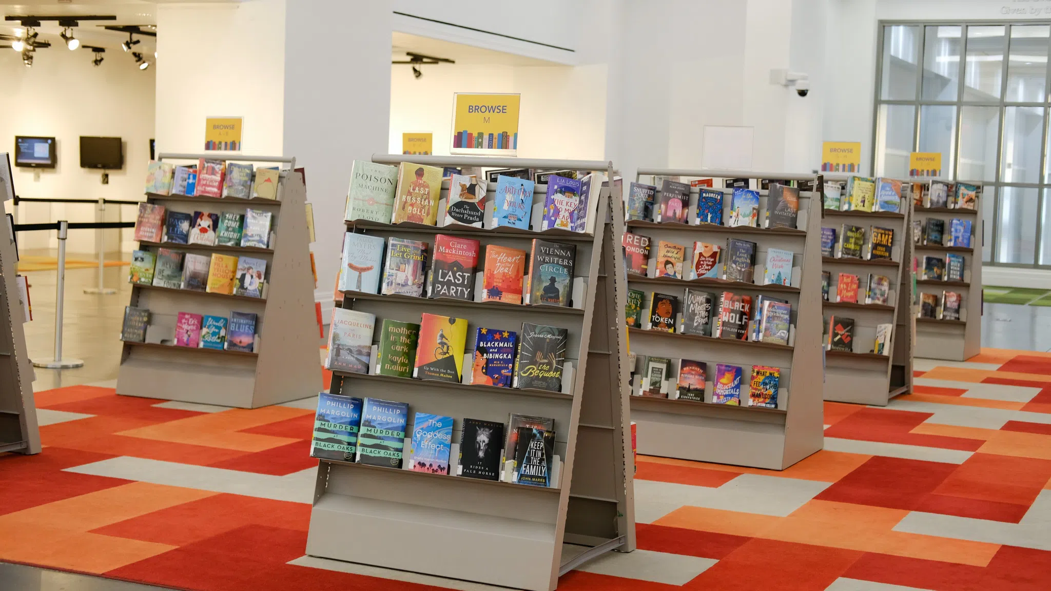 Multiple book cases with fiction-genre books with their covers facing outward.