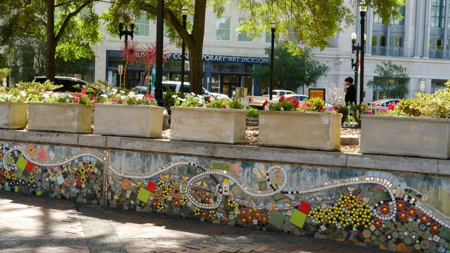 A concrete wall with a colorful mosaic adorning the side.