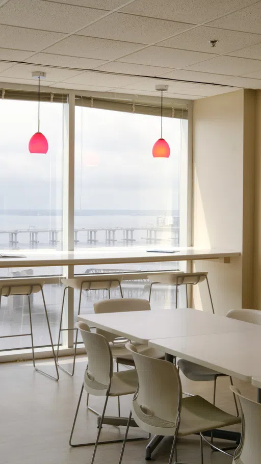 A white lunchroom with tables and chairs arranged in front of a window overlooking the St. John's River.