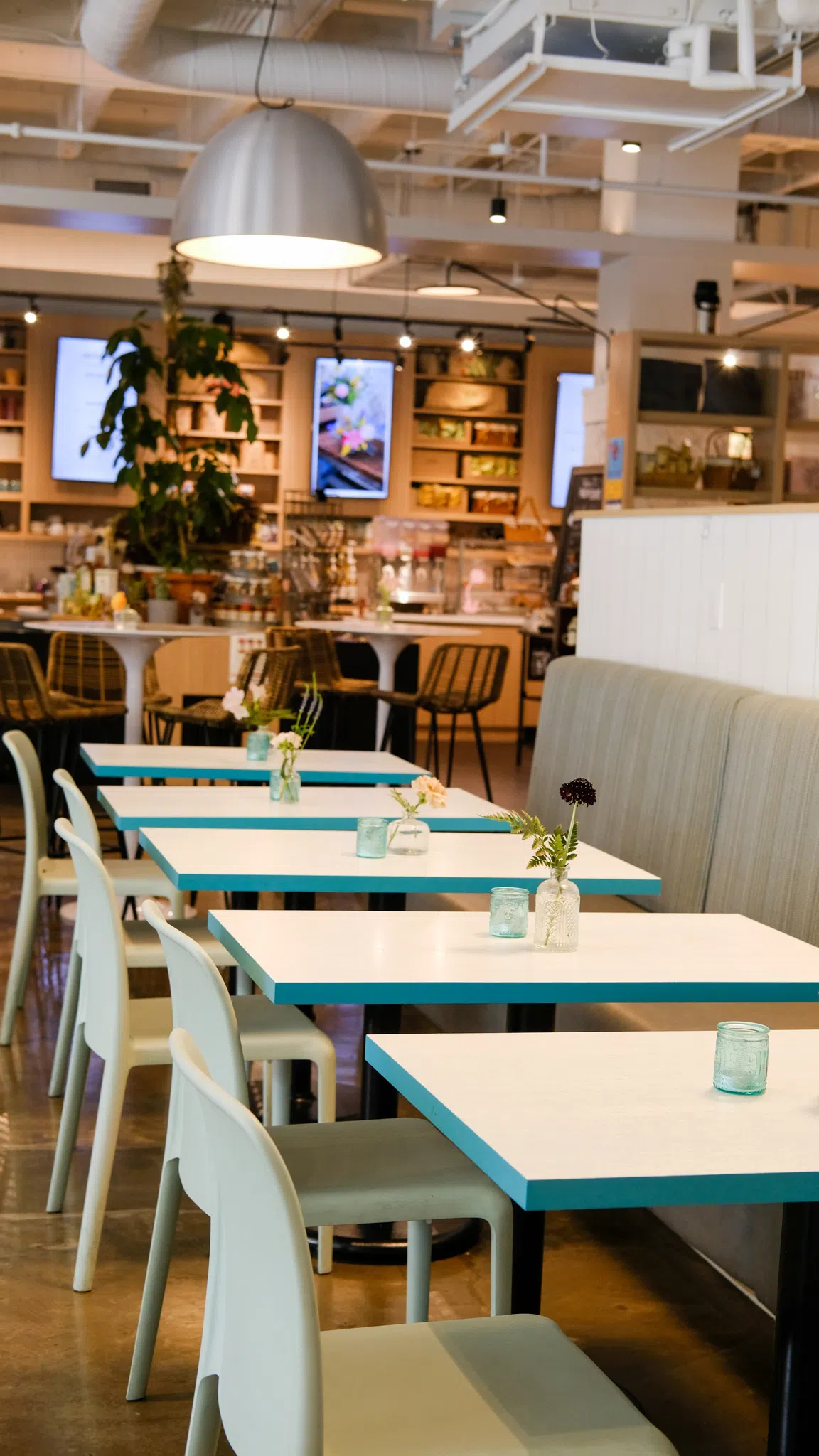 A line of small cafe tables with a booth on one side and chairs situated at the other.