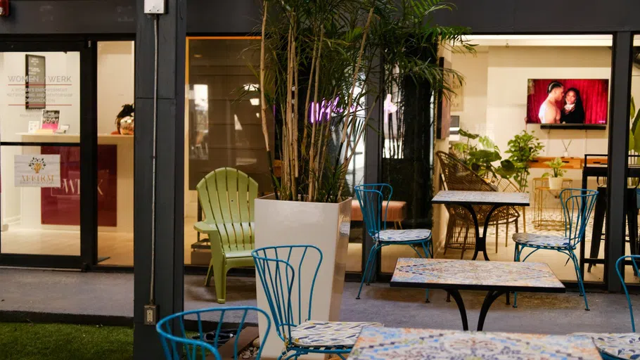 Tables and chairs arranged in an indoor/outdoor hybrid garden.