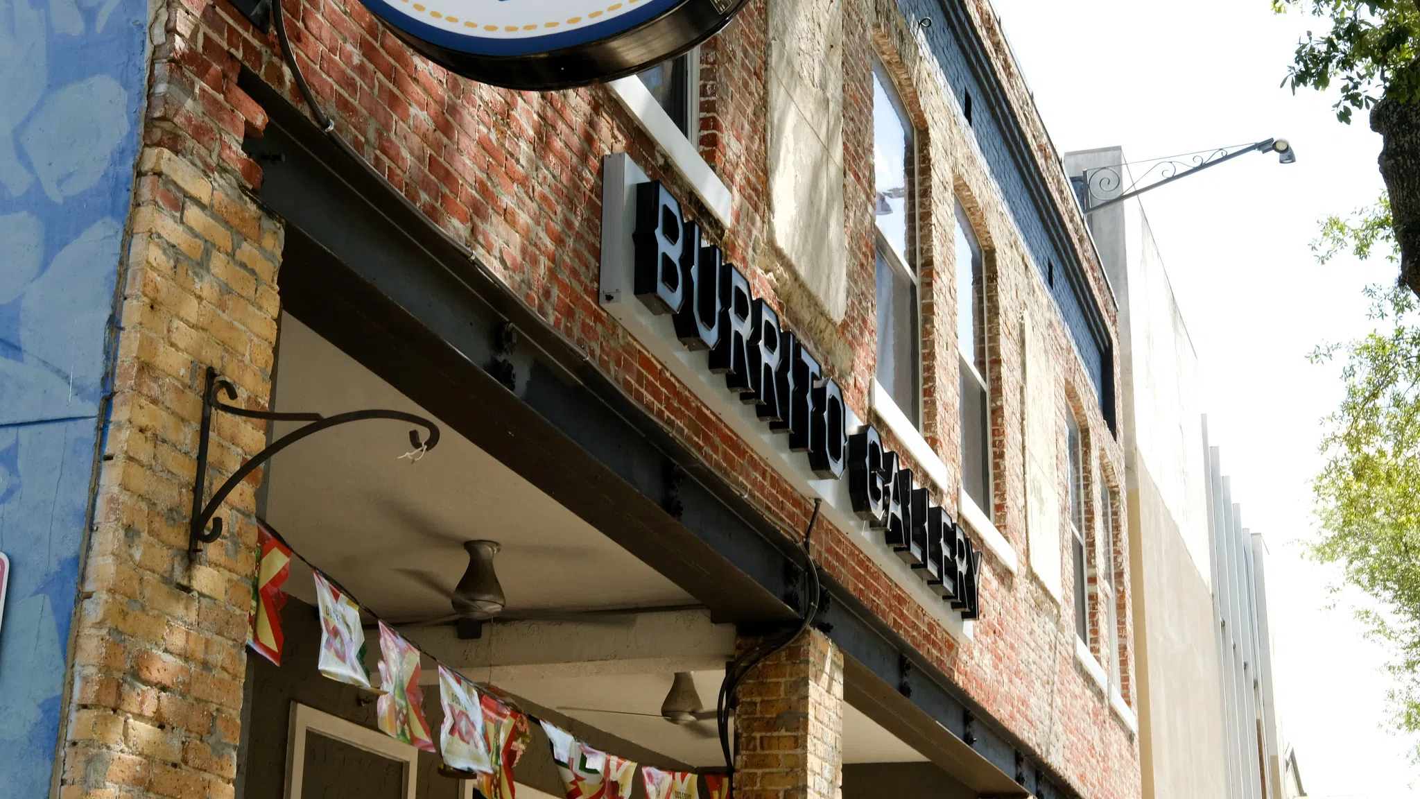 A brick building with a small patio in front. A sugar skull logo extends from the building.