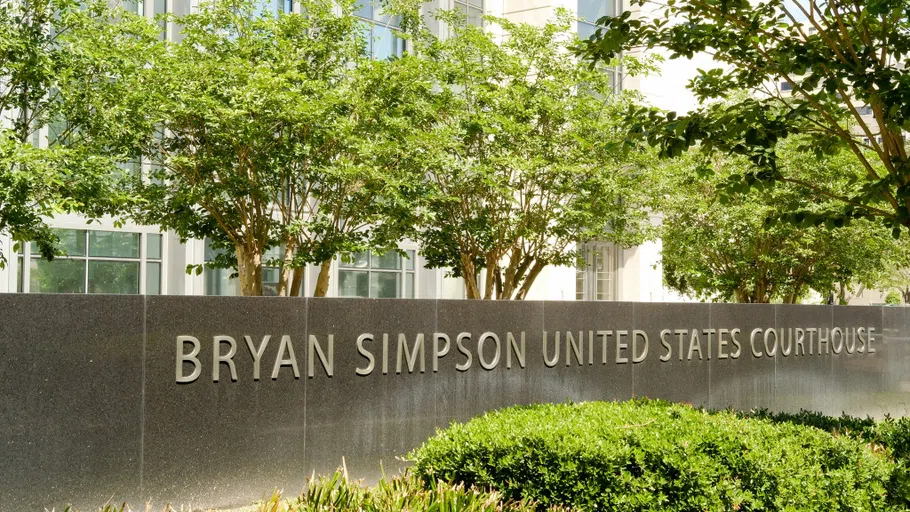 A long, stone sign in the front of a courthouse building that reads "Bryan Simpson United States Courthouse."