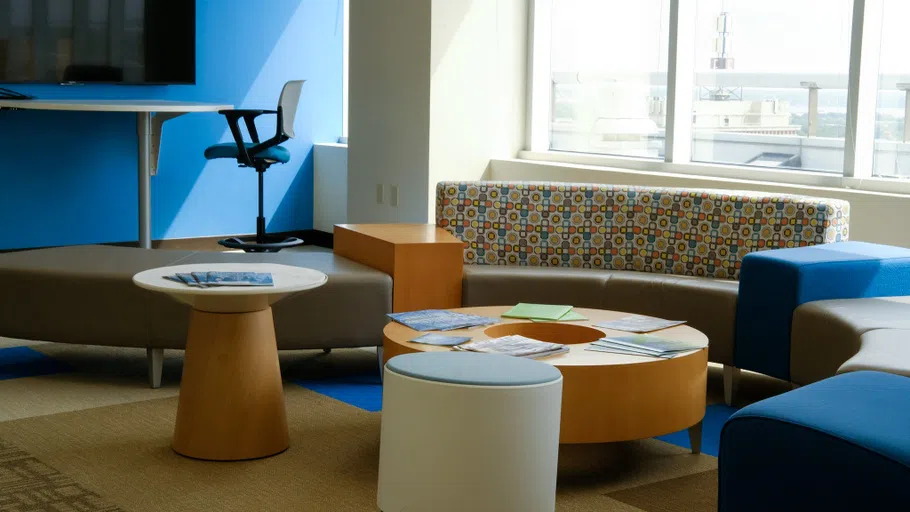 A room with multiple seating areas, a coffee table, and a work table with chairs and a television where students can work and use the technology for group work.