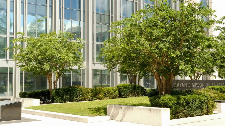 A white building with many windows, and a large courtyard area in the front.