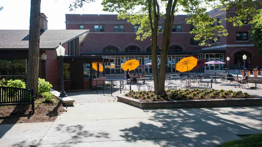 Students find shade on a summer afternoon under the purple and gold umbrellas on the Gizmo Patio outside Seymour Union.