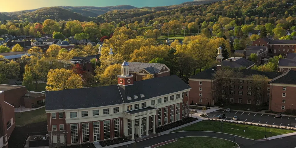 Aerial view of Lycoming campus with Krapf Gateway Center in the foreground and colorful mountains in the background.