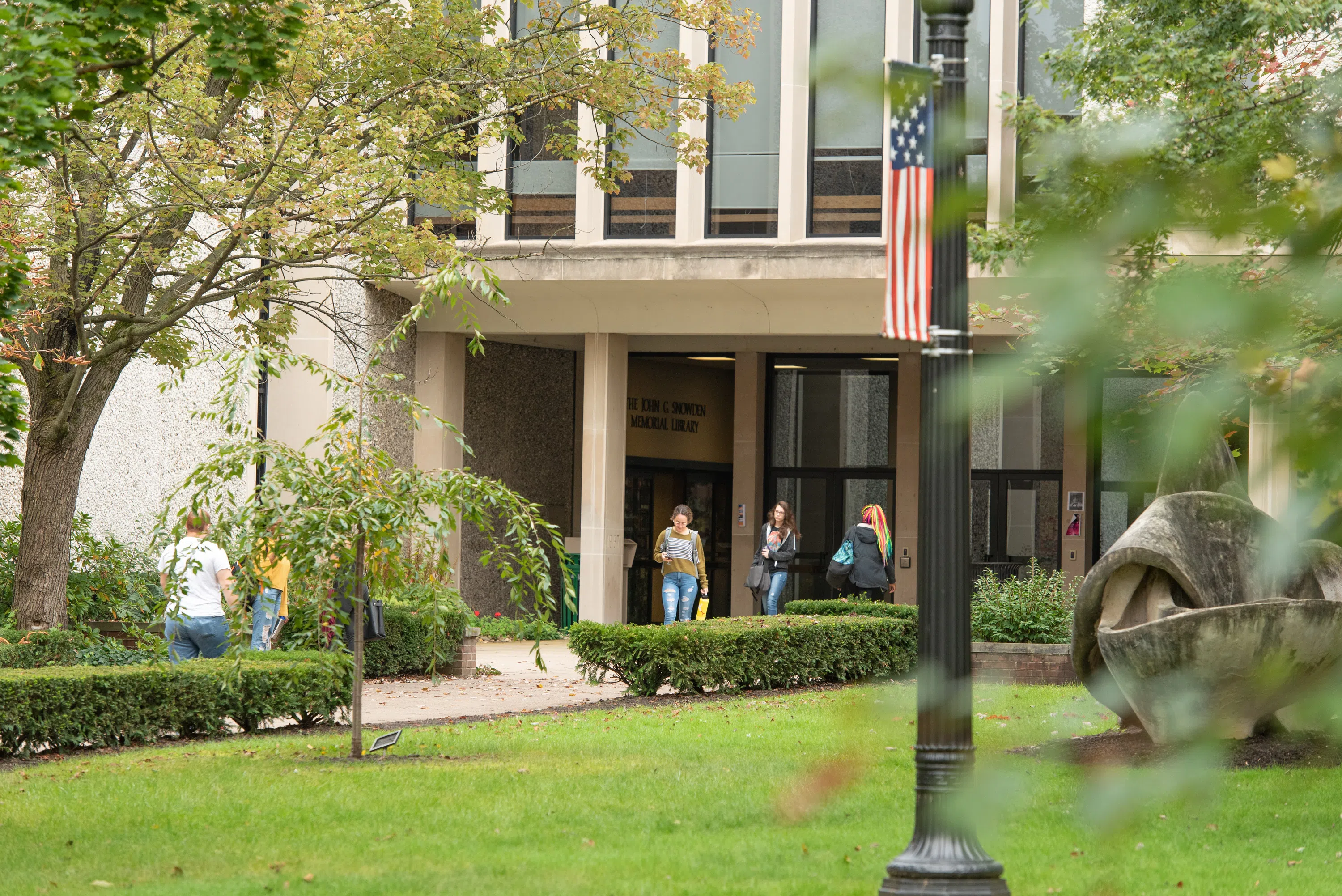 Students entering and exiting Wendle Hall Academic Center on a fall day.