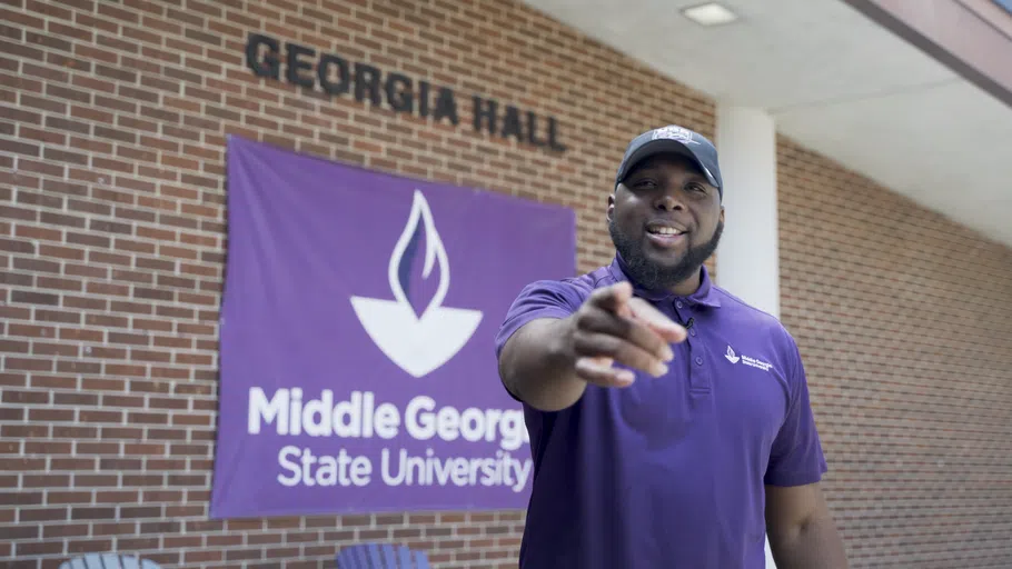 Faculty member poses next to the Georgia Hall building entrance.