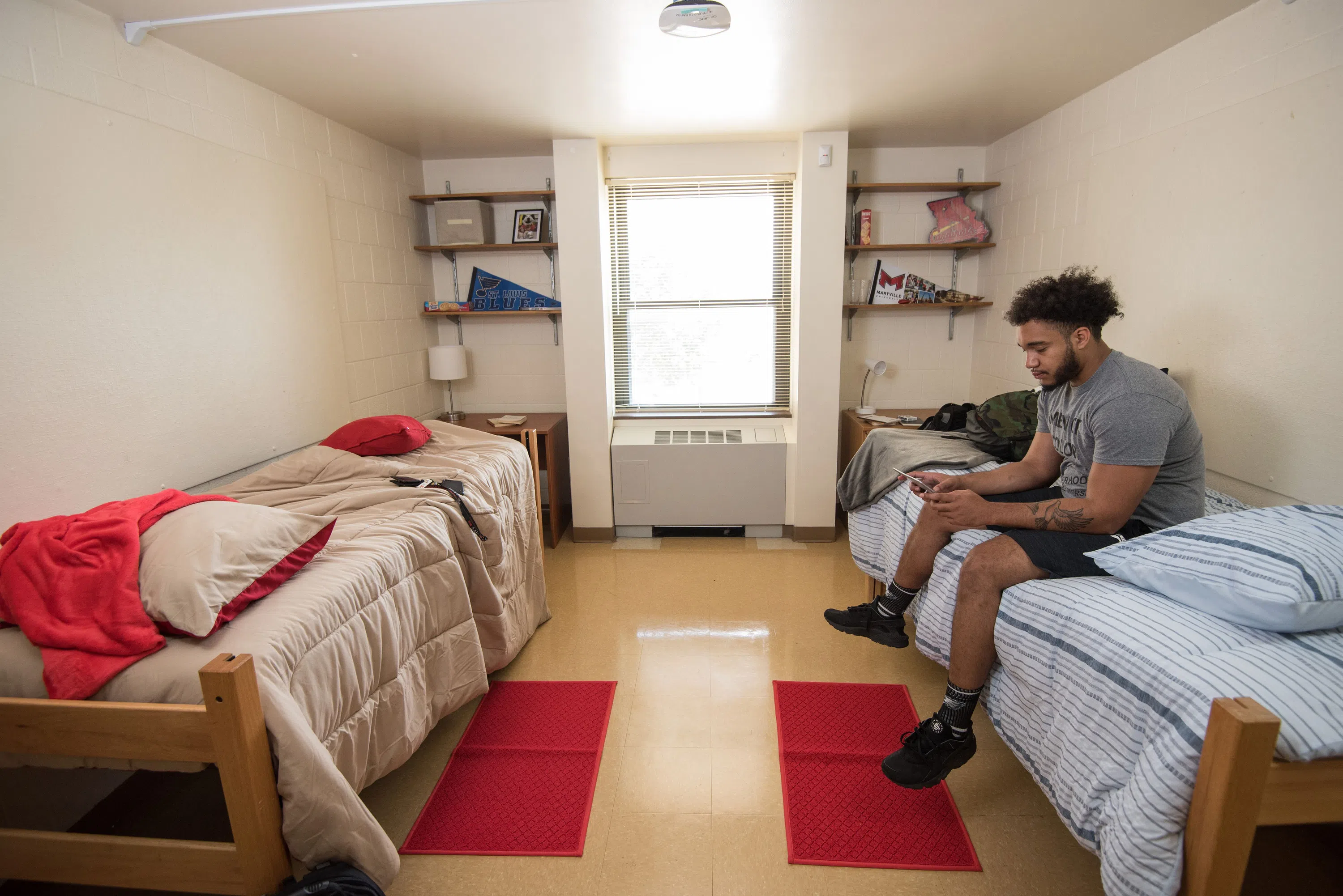 A student sits on a bed in one of the double rooms in Mouton Hall. 