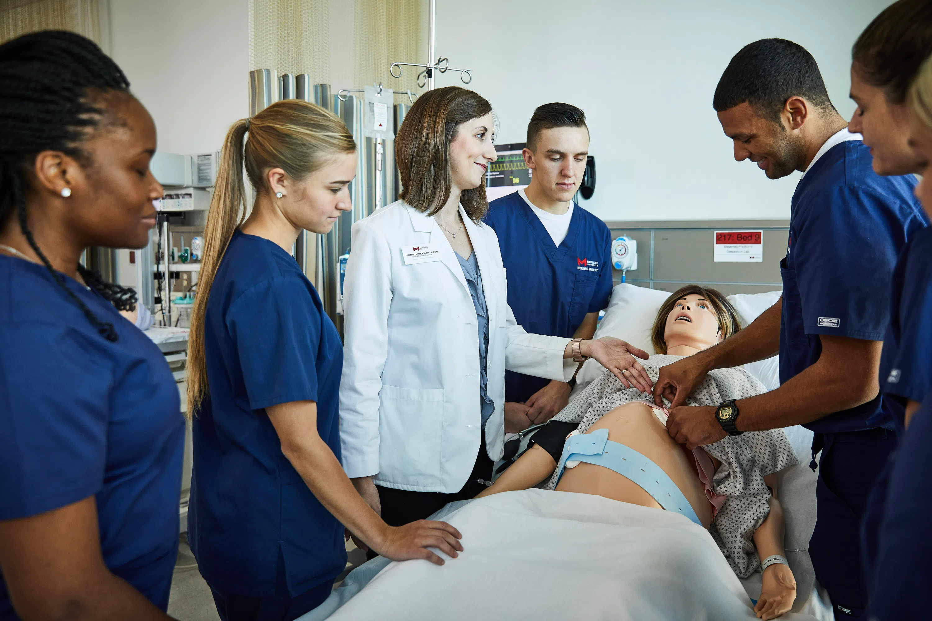 Students gather around a pregnant mannequin. This mannequin will simulate a birth and allow students to experience what it might be like to be a nurse in a hospital setting. 