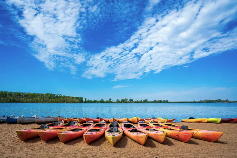 kayaks lines up in front of a beautiful blue lake