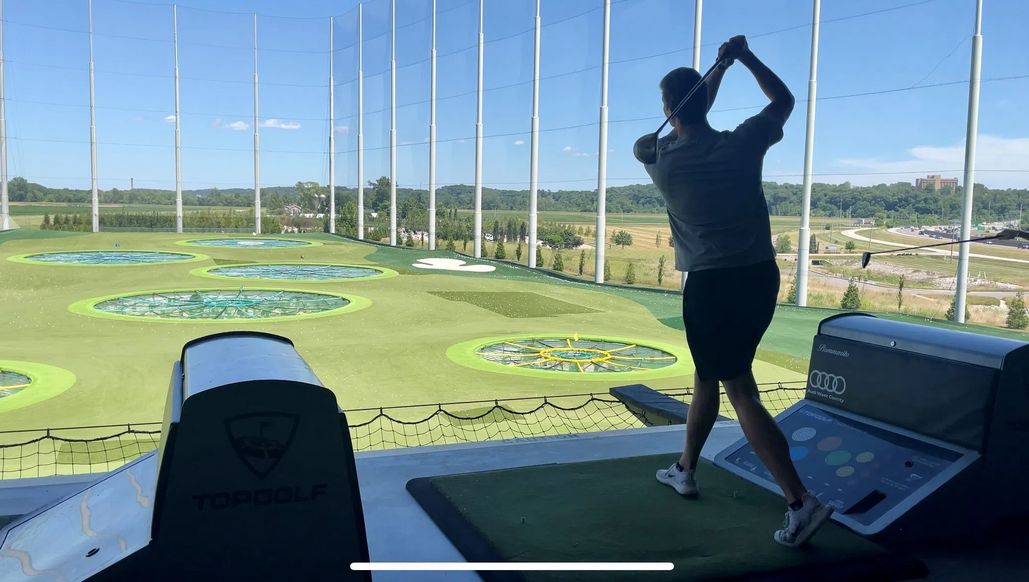 A student swings and hits a golf ball while playing Top Golf