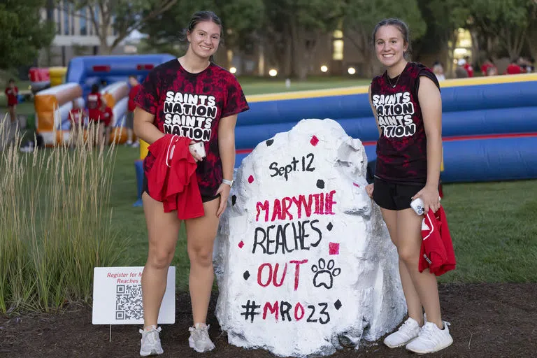 Two students stand next to the Sprit Rock that says "Maryville Reaches Out"