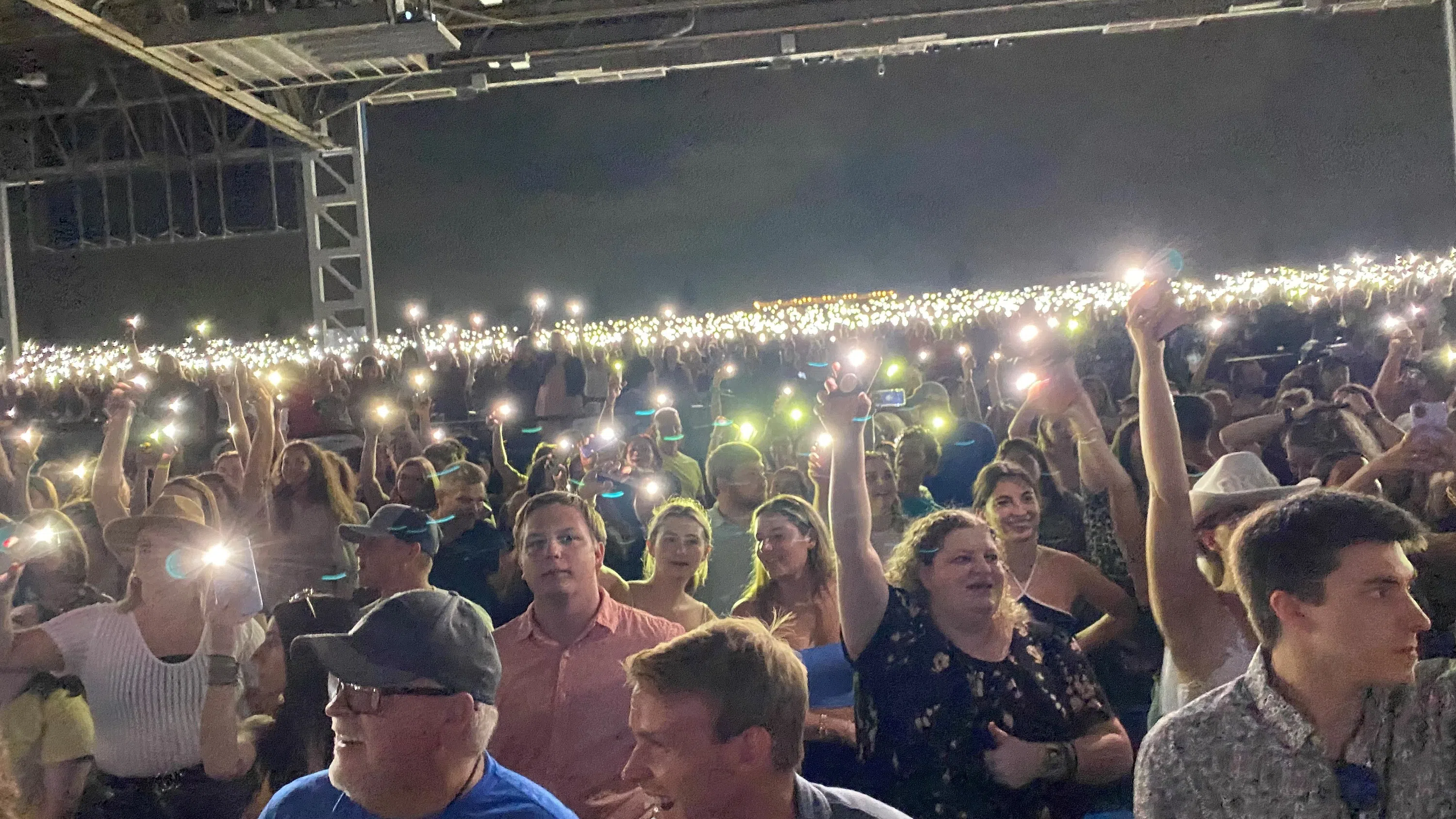 The crowd holds up their phones during a song